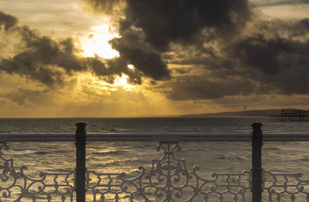 View of sea and sunset sky with golden light and fenceの写真素材