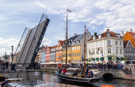 COPENHAGEN, DENMARK - JUNE 17 2018: Boat sailing through pass the opening bridge at Nyhavn with the...