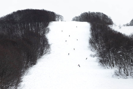 People skiing and snowboarding on ski slope on snow mountainの写真素材