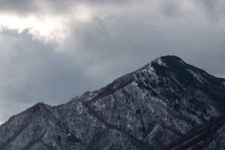 Landscape view of close-up snow covered mountain range in winter with overcast sky backgroundの写真素材