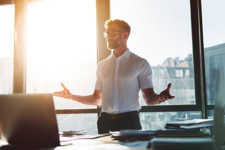 A professional man in short sleeves giving presentation in bright office settingの素材