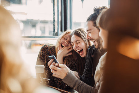 A joyful friends laughing together in cozy cafe, sharing fun moment with drinksの素材