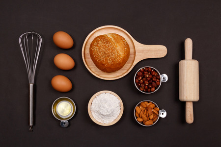 Homemade breads or bun, croissant and bakery ingredients, flour, almond nuts, hazelnuts, eggs on dark background, Bakery background frame, Cooking breakfast concept. Flat lay, Top view and copy space.の写真素材