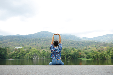 Happy woman relaxing in park and breathing fresh air outdoors. Enjoying life. Back side of young woman looking at the lagoon. Vacations lifestyle concept.の写真素材