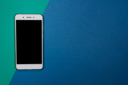Smartphone or Mobile phone on green and blue background with copy space. Flat lay. Top view.の写真素材