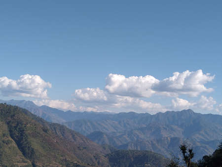 mountains covered trees and sky with cloudの写真素材