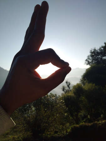 Low Angle View Of Silhouette Hand Holding Sun During Sunsetの写真素材