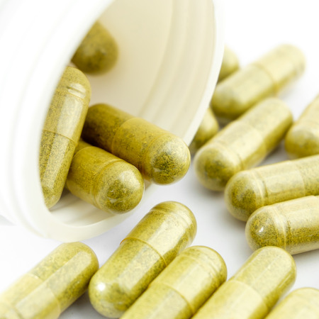 Herbal medicine capsules spilling out of a bottleの写真素材