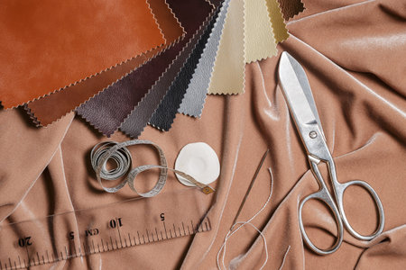 Scissors, leather samples and sewing accessories on a fabric background. Top view.
