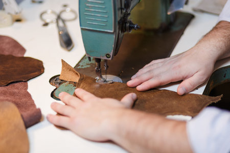 Tailoring process - men's hands behind sewing leather. Selective focus