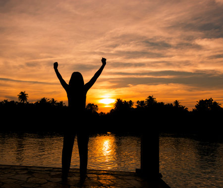 The success concept of silhouette of Young woman standing arms made Under the Rising Sunの写真素材