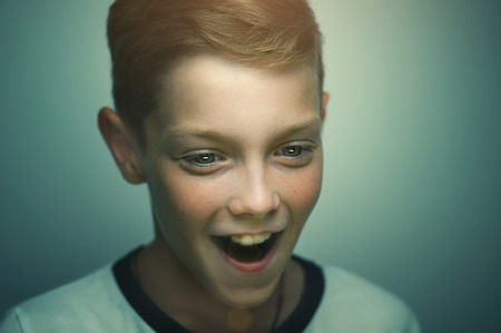 Surprised blond happy teenage boy with stylish haircut and bright eyes, studio portrait.の写真素材