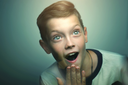 Surprised blond happy teenage boy with stylish haircut and bright eyes.の写真素材