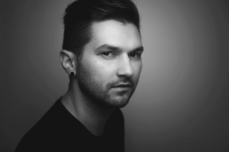 Black and white portrait of a serious young hipster handsome man looking at you, side view.の写真素材