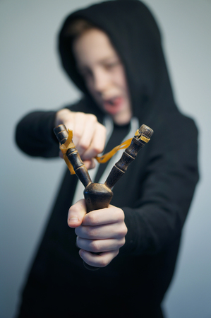 Portrait of a handsome teenage bad boy with slingshot and stylish haircut, softbox lighting studio shot.の写真素材