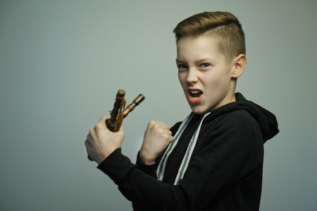 Portrait of a handsome teenage bad boy with slingshot and stylish haircut, softbox lighting studio shot.の写真素材