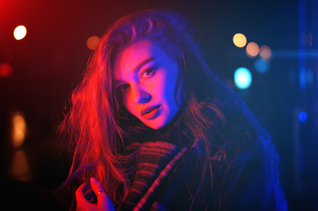 Sexy young beauty woman posing over night city dramatic red and blue neon backgroundの写真素材