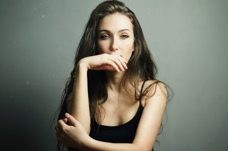 Young gorgeous sad brunette girl with beautiful blue eyes and great hair. Sensual studio portrait.の写真素材
