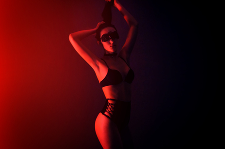 Fashion art photo of elegant model in seductive black lingerie with light neon colored club spotlightsの写真素材