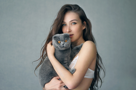 Sexy beautiful brunette girl in underclothes with cute cat resting at home studioの写真素材