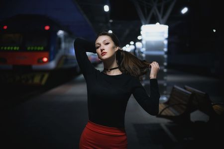 Beautiful young elegant woman traveler waiting for train at evening train stationの写真素材