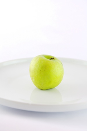 Green apple on white plateの写真素材