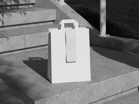 White Paper Shopping Bag with Receipt on Stairs. Black and White Image. 3D Rendering.の写真素材