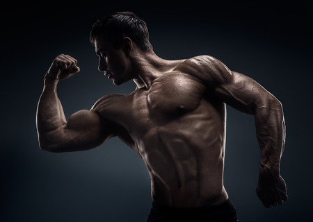 Handsome muscular bodybuilder posing over black backgroundの写真素材