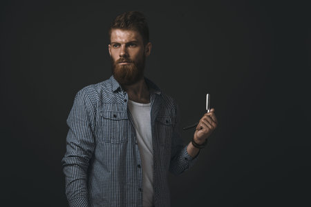 Brutal bearded man with straight razor