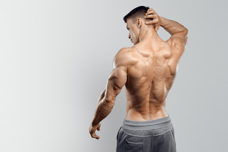 Shirtless athletic man turned back on white background.の写真素材
