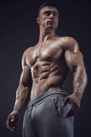 Close-up of a power fitness man. Strong and handsome young man with muscles and biceps. Studio shooting on black background.の写真素材
