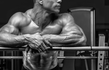 Close up of handsome bodybuilder guy prepare to do exercises with barbell in a gym. Black and white photo.の写真素材