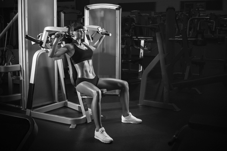 Strong young woman with beautiful athletic body doing exercises special sport equipment in the gym. Black and white photoの写真素材
