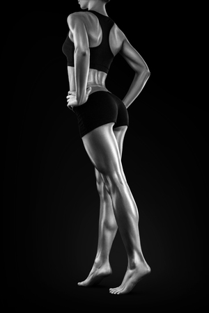 Perfect shaped woman walking on black background. Torning back and perfect fit long woman legs showing. Black and white photo.の写真素材