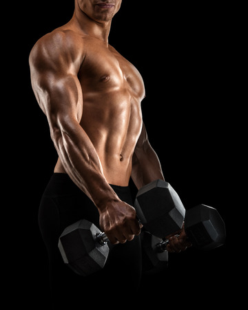 Close-up of handsome power athletic mans hand in training pumping up muscles with dumbbell. Strong bodybuilder with six pack, perfect abs, shoulders, biceps, triceps and chestの写真素材