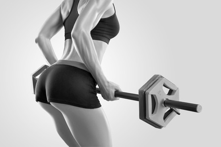 Black and white closeup portrait of perfect fit athletic young woman workout with barbell at gym.の写真素材