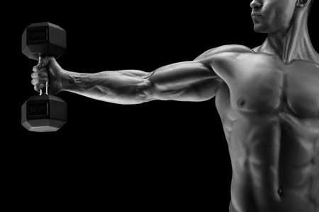 Close-up of a power fitness man's hand with dumbbell. Strong bodybuilder with six pack, perfect abs, shoulders, biceps, triceps and chest, deltoid muscle. Black and white photo.の写真素材