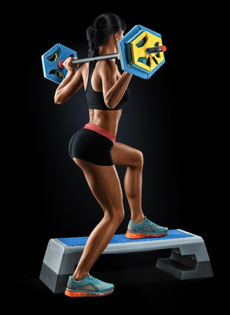 Beautiful fitness woman preparing to lift some heavy weights. Strong young woman with beautiful athletic body doing exercises with barbell.の写真素材