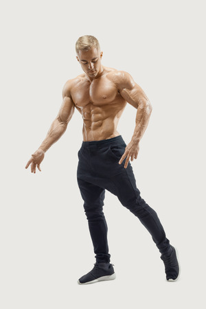 Full-length shot of handsome young man with muscular body standing against white background. Perfect fit, six pack, abs, abdominal muscle, shoulders, deltoids, biceps. Vector mask clipping pathの写真素材