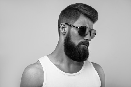 Bearded man wearing sunglasses. Black and white studio shot on white backgroundの写真素材