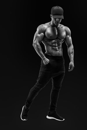 Black and white portrait of shirtless male bodybuilder with muscular physique posing with muscular build strong abs showing Masculine young fitness male model posing shirtless against black backgroundの写真素材