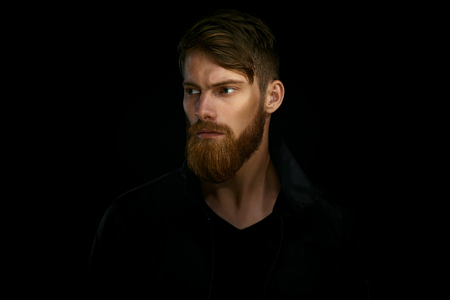 Close-up portrait of bearded handsome man in a pensive mood looking awayの写真素材