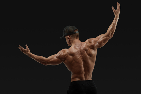 Shot of healthy muscular young man turning back and rise both hands. Perfect fit, six pack, abs, abdominal muscle, shoulders, deltoids, biceps. Vector path clipping maskの写真素材