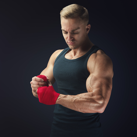 Strong man wrap hands on black background Man is wrapping hands with red boxing wraps isolated on black background Strong hands and fist, ready for training and active exerciseの写真素材