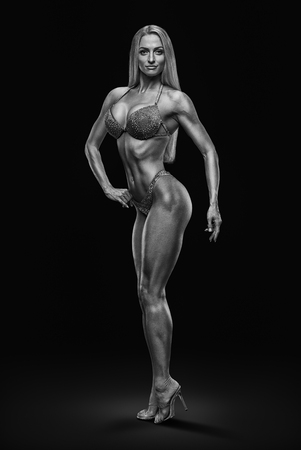 Black and white full size photo of fitness bikini model Confident attractive young female bodybuilder posing slim body perfect shape Muscular abs legs booty arms chest Sporty women on black backgroundの写真素材