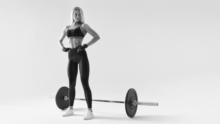 Confident young blonde woman with barbell concept black and white photo Female athlete before exercising with heavy weights at gym Female performing deadlift exercise with weight barの写真素材