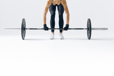 Fitness attractive woman preparing to practice deadlift with heavy weights Female bodybuilder doing heavy weight lifting work out on white background Close-up horizontal pictureの写真素材
