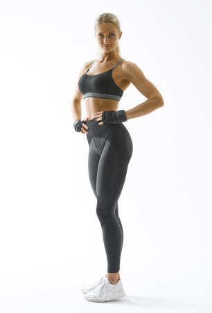 Full length portrait of fitness woman standing with her arms on hips Female model in sportswear over white background Mockupの写真素材