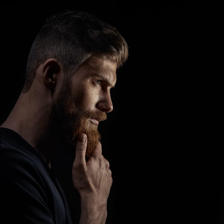 Profile view of handsome stylish young man with undercut hairstyle, beard with copy space