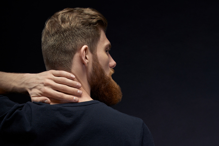 Handsome bearded man turned back. Pour over black background. Young model man with ginger hairの写真素材